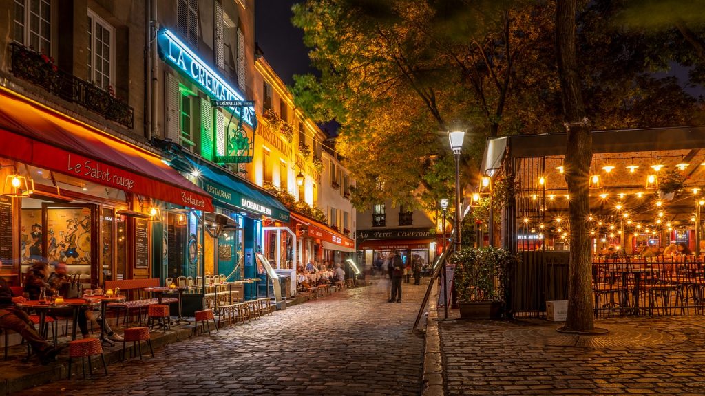 rue parisienne pavée illuminée la nuit avec restaurants et terrasses colorées