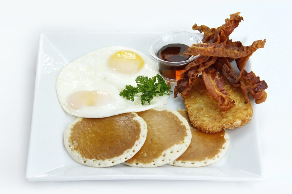 petit-déjeuner américain traditionnel avec œufs, pancakes, bacon et sirop d'érable