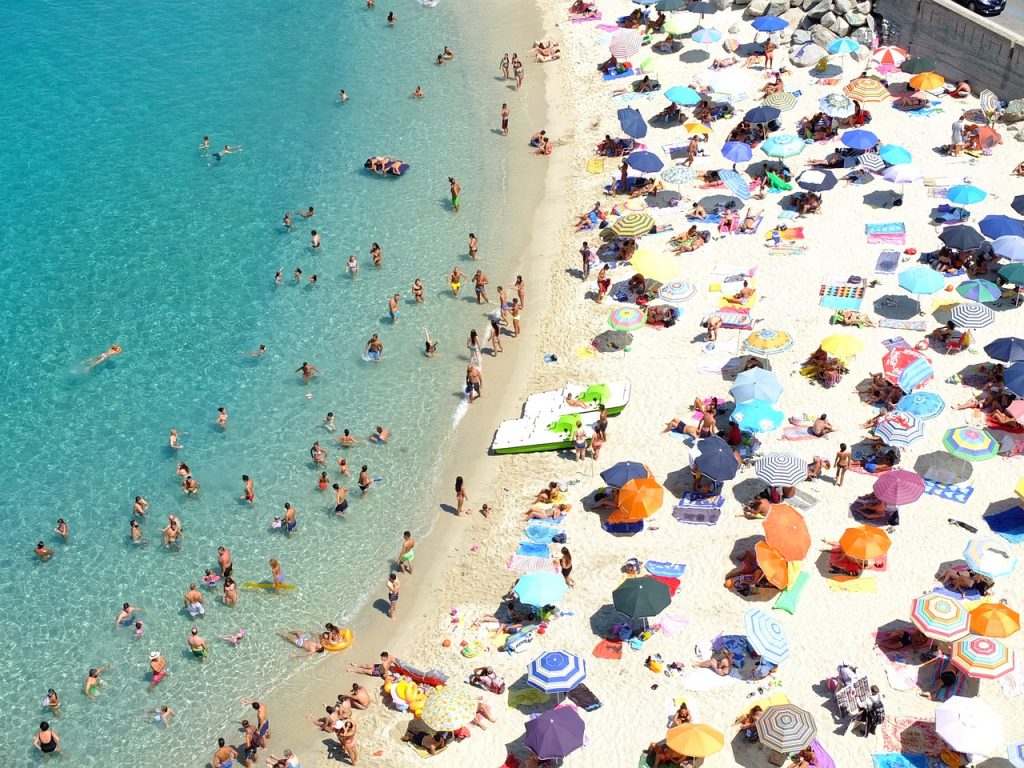 plage italienne bondée avec baigneurs et parasols colorés sur le sable blanc