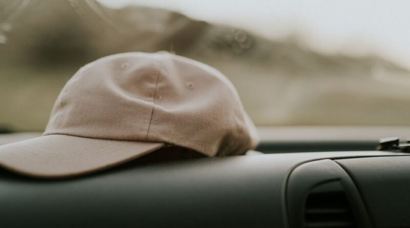 Minimalistic scene of a beige cap on a car dashboard, offering a sense of travel and style.