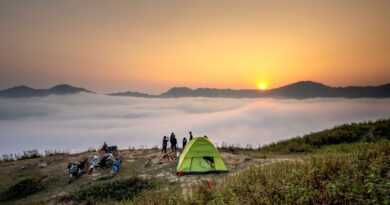 Capture of a serene camping scene at sunrise with a view over a sea of clouds and mountains.