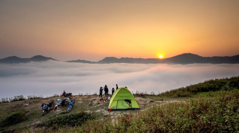 Capture of a serene camping scene at sunrise with a view over a sea of clouds and mountains.