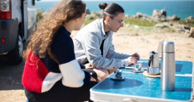 Two people enjoying remote work outdoors by the sea in Portugal.