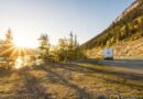 An rv drives along a scenic mountain road at sunset