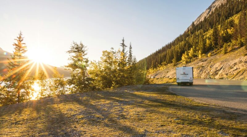 An rv drives along a scenic mountain road at sunset