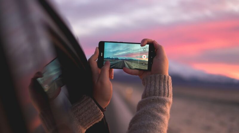 A person captures a stunning Icelandic sunset through a smartphone while traveling.