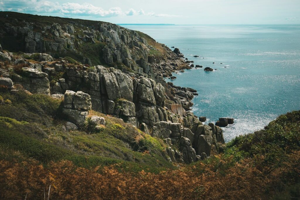 Rugged granite cliffs dropping into the blue sea under a bright sky