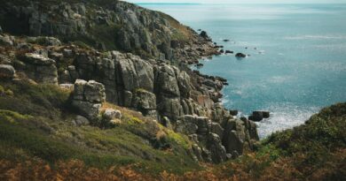 Rugged granite cliffs dropping into the blue sea under a bright sky
