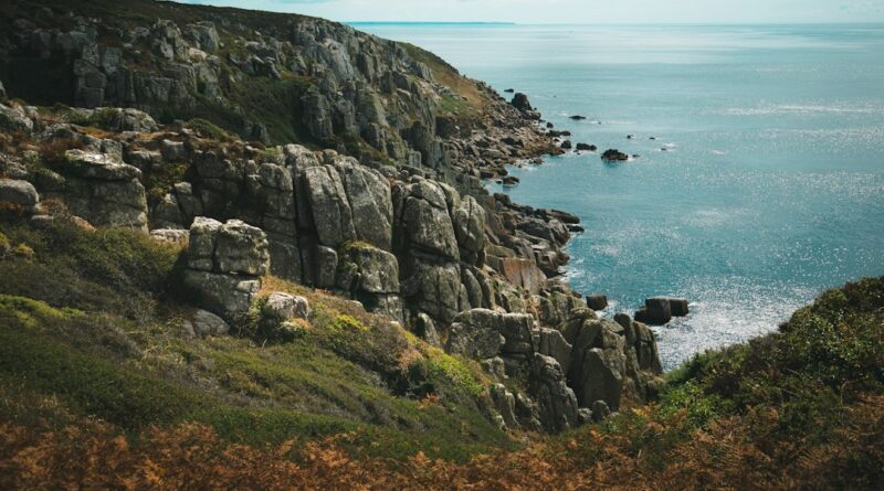 Rugged granite cliffs dropping into the blue sea under a bright sky